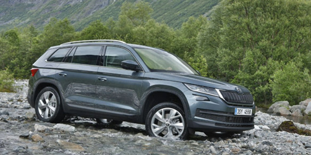 Side view of a dark grey Skoda SUV parked on rugged rocky terrain.