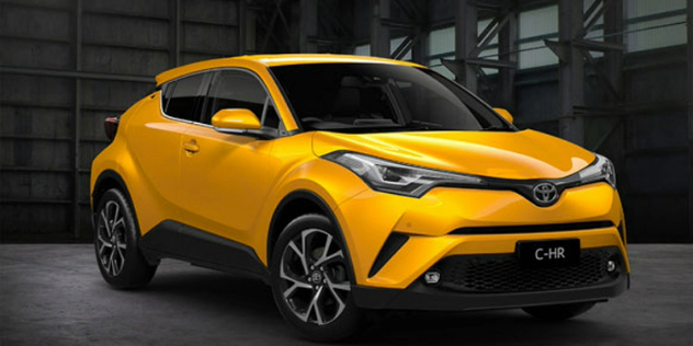 Front-angle view of a yellow Toyota SUV parked in a dimly lit grey warehouse.