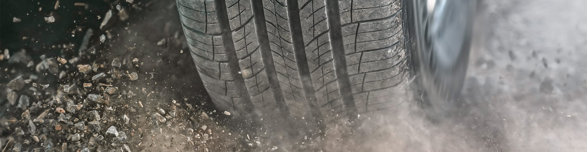 Close up of car tyre tread driving on dirt road