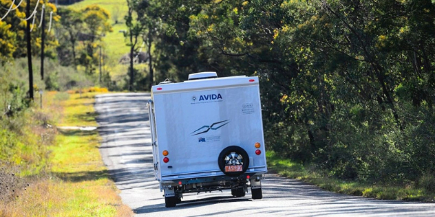 Rear view of a caravan being towed down a country road