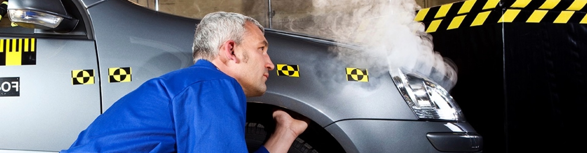 A technician examines a vehicle in a crash-test environment