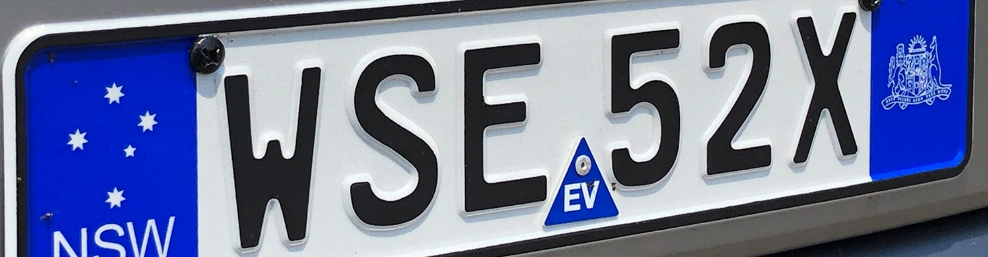 ev-number-plate-labels-1920x500 A New South Wales vehicle number plate, with a blue EV safety sticker in the bottom middle of the plate.