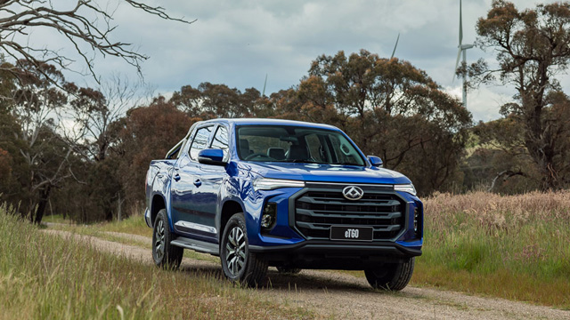 A blue utility vehicle drives along a dirt road