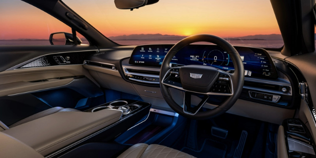 Front interior cabin of a smart SUV with a view of a beautiful orange hued sunset through the windscreen.