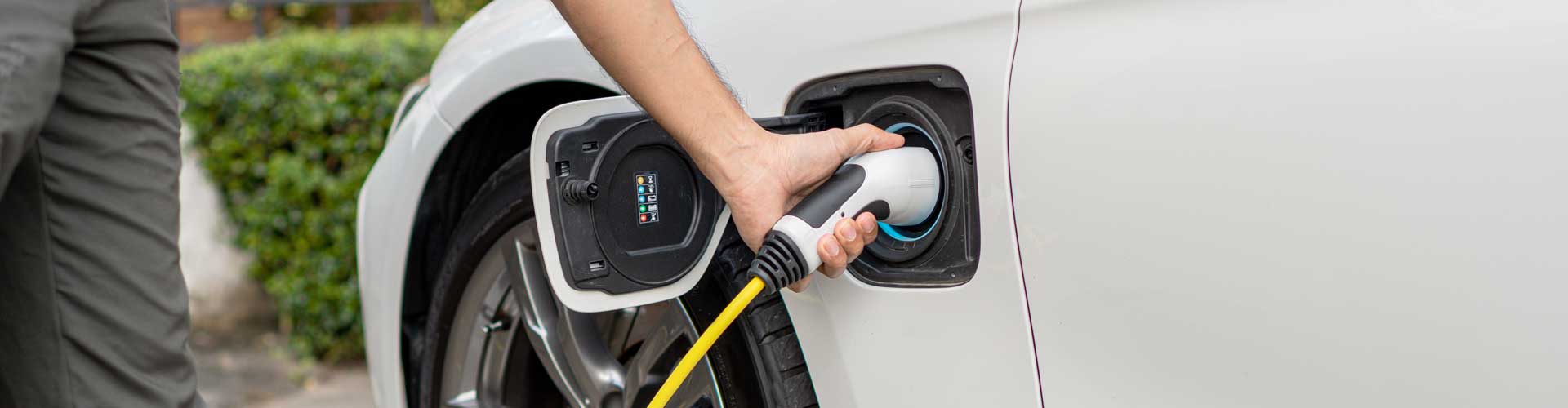 Man's arm seen plugging in EV at home