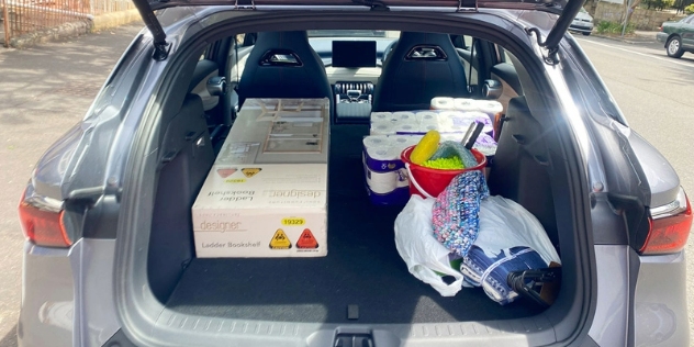 An open boot filled with boxes, toilet paper and cleaning supplies.