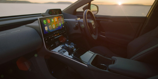 Side view of the front interior of a car with a view of the sunset through the driver's side window.