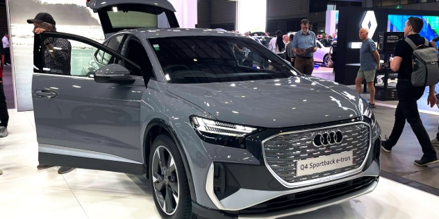 A grey Audi Q4 Sportback e-tron parked in an indoor exhibition with all its doors and boot open.