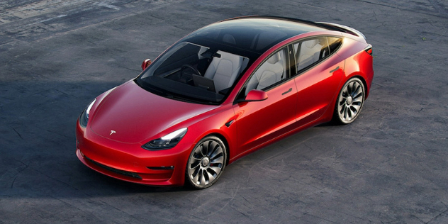 Ariel view of a red Tesla model Y parked in an angle on a black tarred surface.