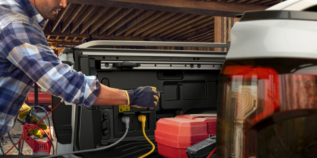 A man plugging an electric device in the bin of his Ford Ranger ute.