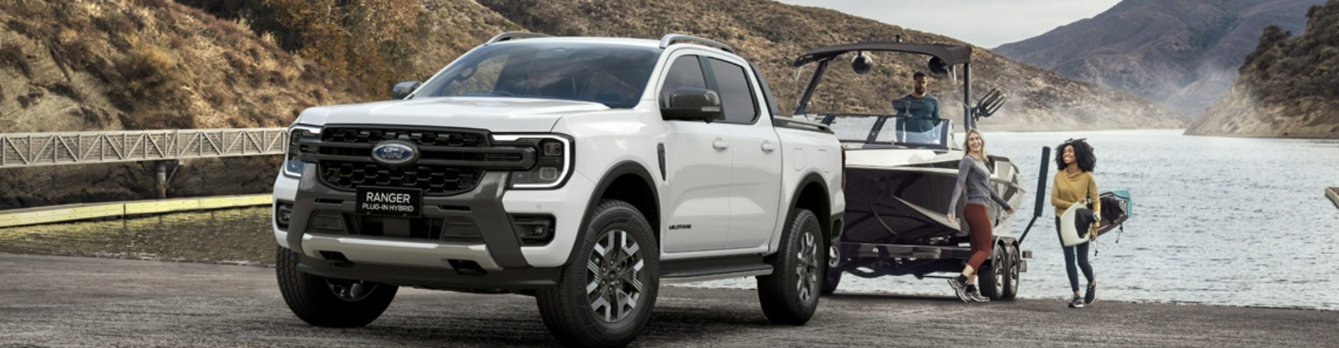 A white Ford Ranger ute reversed into a boat ramp, with a boat hitched to it.