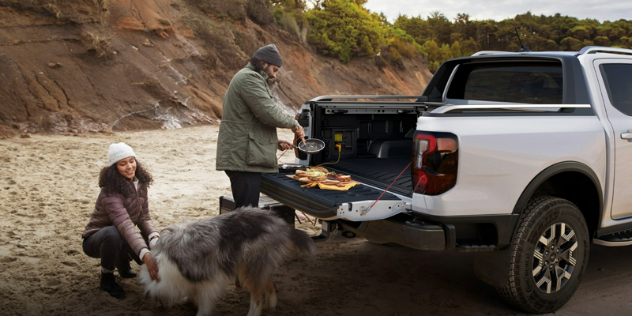 A white Ford Ranger ute parked on a beach with the bin open. 