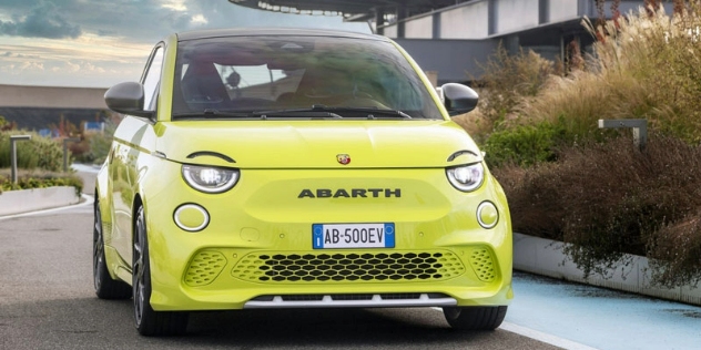 Front view of a neon green Abarth driving along a road.