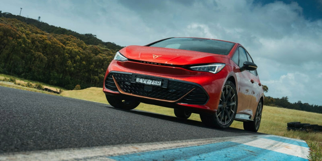 Front view of a red Cupra Born driving along a road.