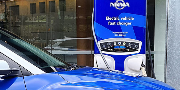 NRMA's Hyundai Kona EV at a blue NRMA EV charging station in Sydney Olympic Park