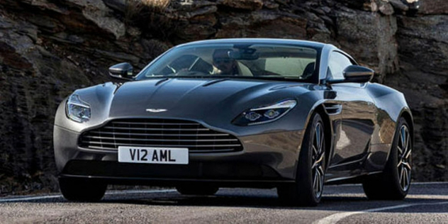 Front-view of an Aston Martin on a road, with a mountain terrain background.