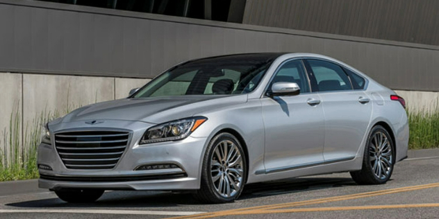 A silver sedan parked next a grey wall.