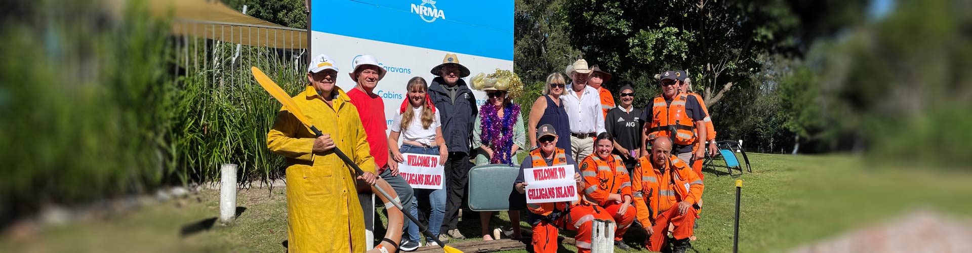 A group of people gather in front of an NRMA parks and resorts sign