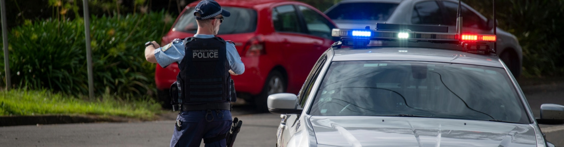 A police officer stands beside a police car