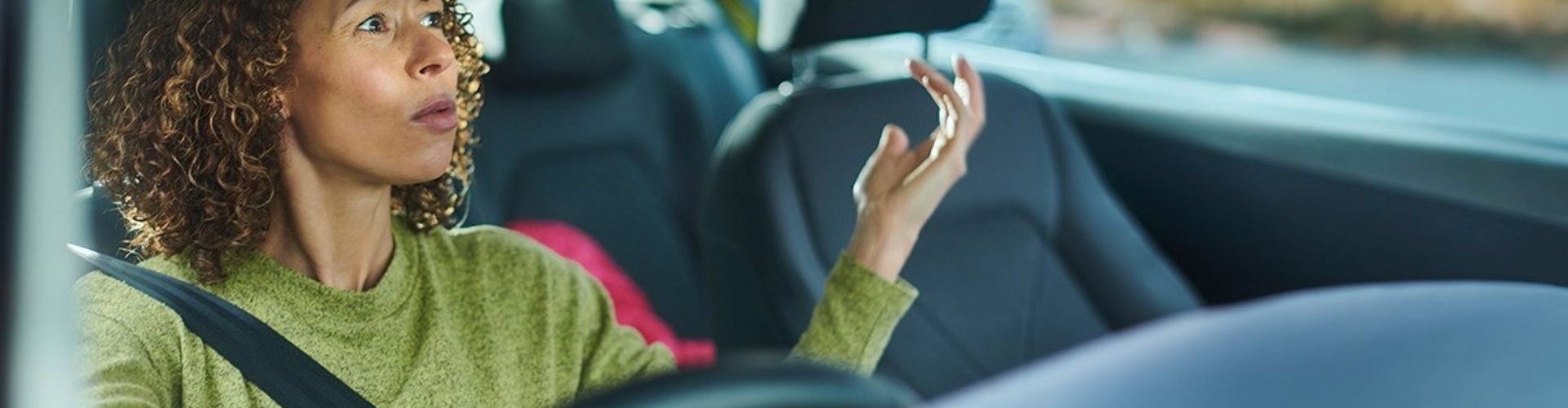 A seemingly frustrated driver looks into her rearview mirror making hand gestures