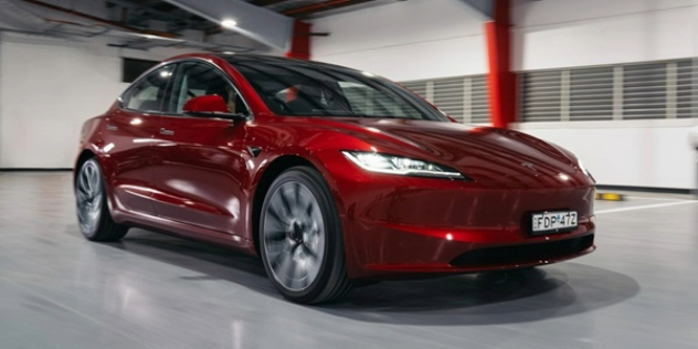 A red Tesla parked in an open space.