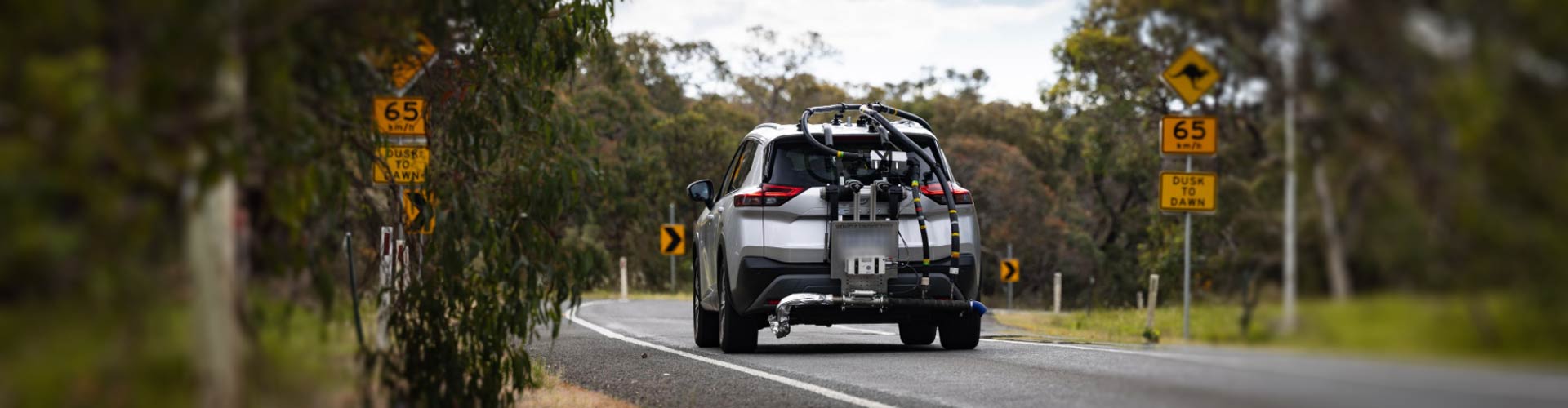 An SUV drives on a country road with texting equipment on its rear