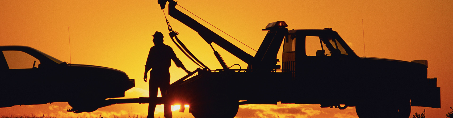 Tow truck towing a car in the sunset