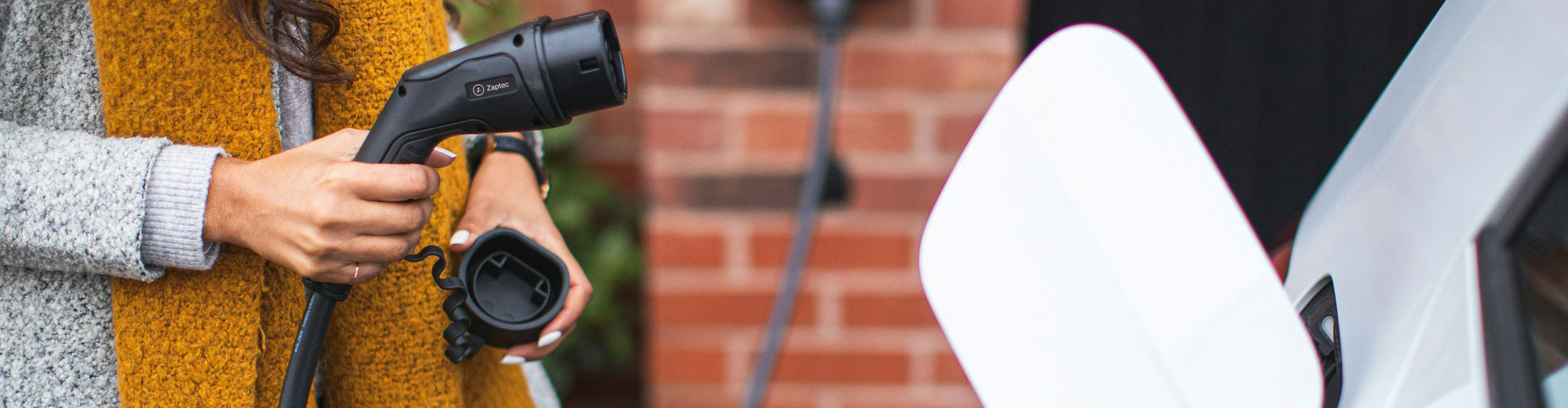 Woman with an orange scarf holding an EV charger cable