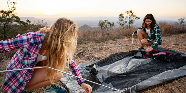 Two women putting up a tent 