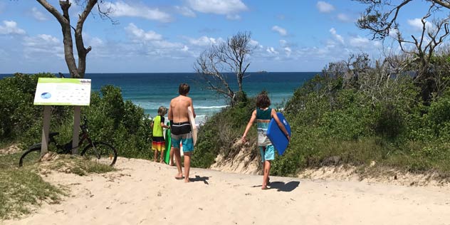 Three boys with boogie boards head down to Belongil Beach