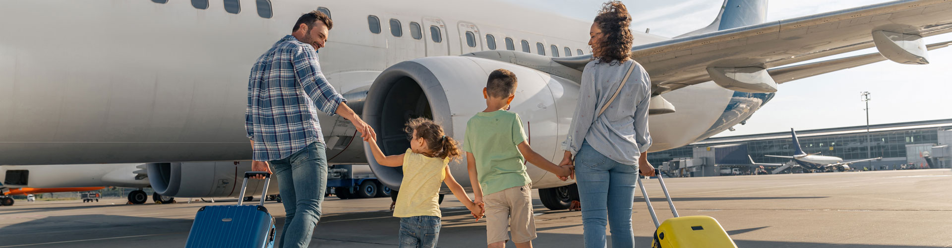 Family of four boarding a plane with yellow and blue carry on bags