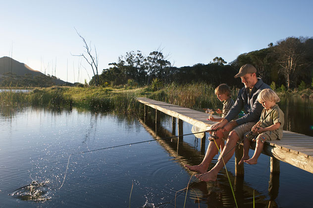 Father and sons aged 2-4 fishing on jetty
