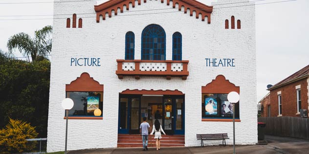 Old picture theatre building with people walking in the front door