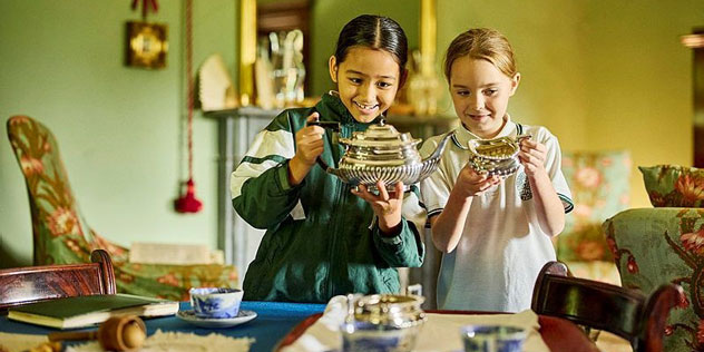 Two girls smile looking at historical models