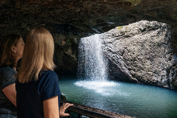 Two women view the Natural Bridge waterfall in southeast Queensland