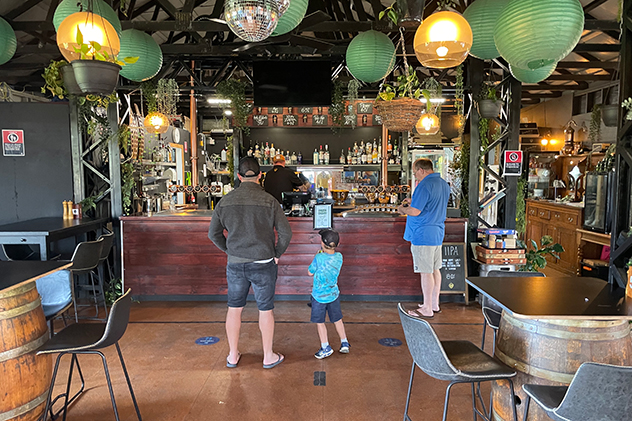 Three people waiting at a bar.