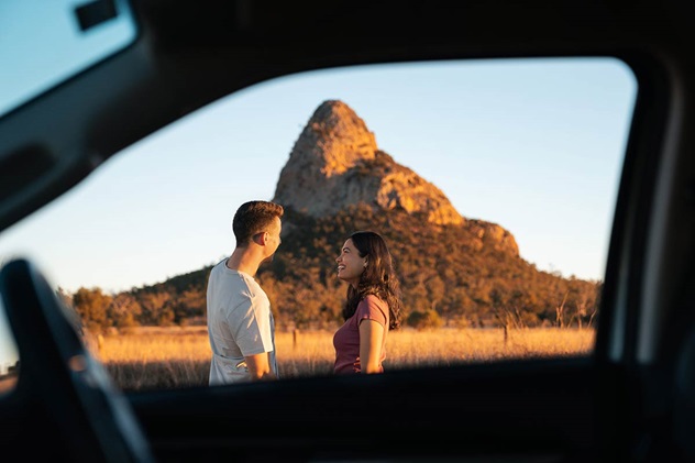 A mountain behind a couple seen from inside their car