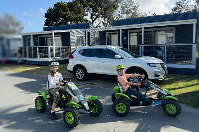 Two children on push pedal karts at a holiday park