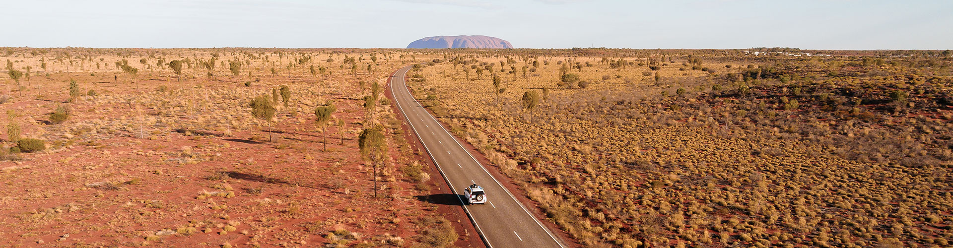 Landscape panorama of a car on a road trip to Ayer's Rock in Uluru in the Red Centre of Australia