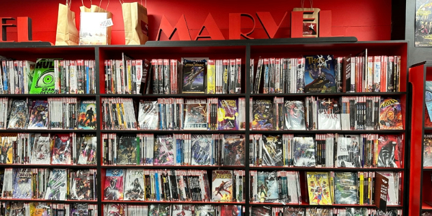 Rows of comic books on shelves, with a sign saying Marvel above them. 