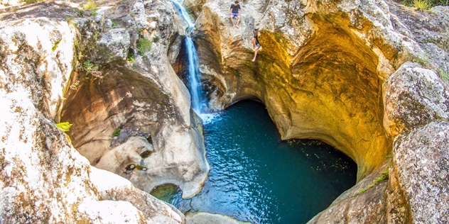 looking down into a natural heart shaped pool with turquoise water and waterfall