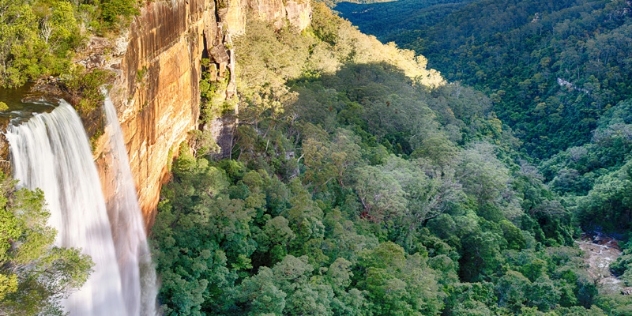 arial view of the Fitzroy Falls waterfall spilling down a sandstone rockface into a valley of trees