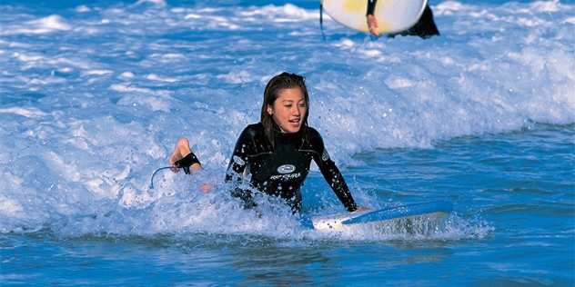 woman in black wetsuit happy after riding a wave