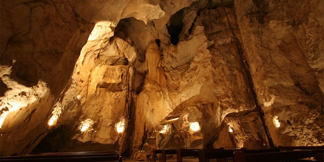 lights spaced at regular intervals on the rock wall illuminate the high ceiling of the Cathedral Cave