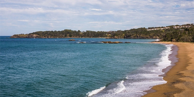 daytime empty beach with headland and ocean in view