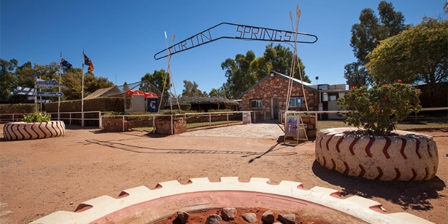 Outside view of Curtin Springs Wayside Inn gateway with a sign shaped like a boomerang