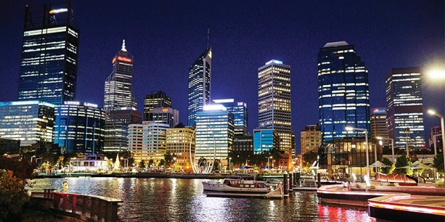 city skyline reflects in the water at night at Elizabeth Quay