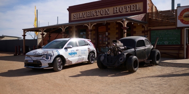 white NRMA electric vehicle parked next to a black hot rod outside the heritage Silverton Hotel