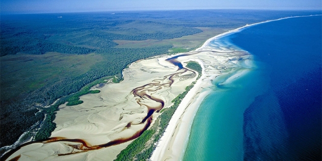 arial view at Fraser Island coastline with rippled sand and clear turquoise and deep blue water