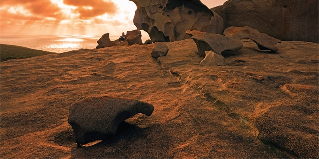 granite rocks with unusual, eroded patterns at sunset with ocean in the background